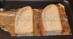 На противень постелена фольга и на нее выложен хлеб