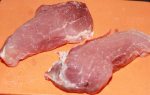 Два свиных стейка лежат на разделочной доске