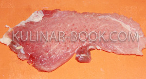 Отбитый свиной стейк лежит на разделочной доске